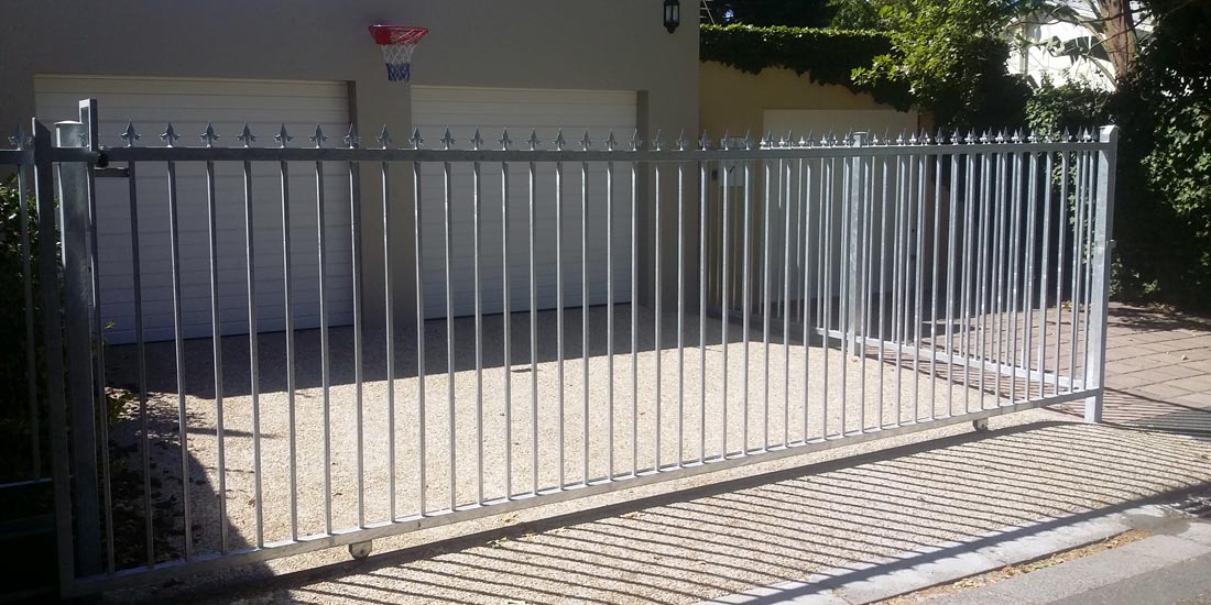 Wide steel sliding gate with round base fleur de lis spikes